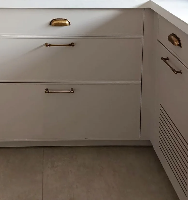 Delgado slim shaker drawer fronts in light grey with brass pulls, in a real kitchen