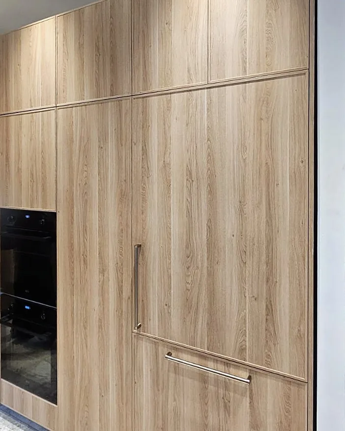 Floor-to-ceiling Delgado tall units in a light woodgrain finish with integrated appliance panels