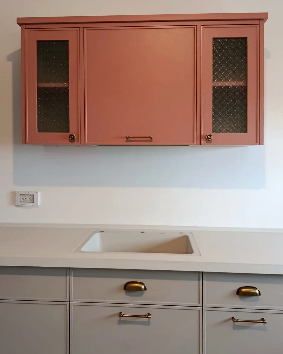 Terracotta vitrine wall cabinet with glass doors over light grey Delgado slim shaker base units
